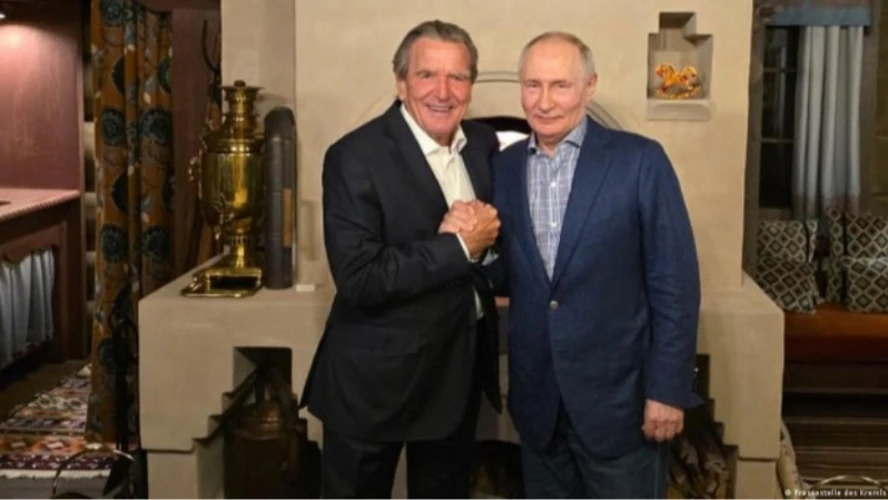 Путін і Шредер біля традиційної російської печі з самоваром і валянками